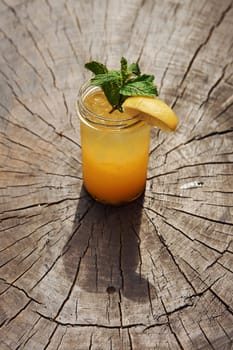 With lemon and mint. Close up view of fresh summer alcoholic cocktail on the wooden table.