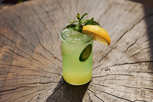 With lemon and mint. Close up view of fresh summer alcoholic cocktail on the wooden table.
