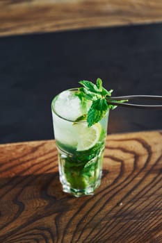 Close up view of fresh summer non alcoholic mojito cocktail on the wooden table.