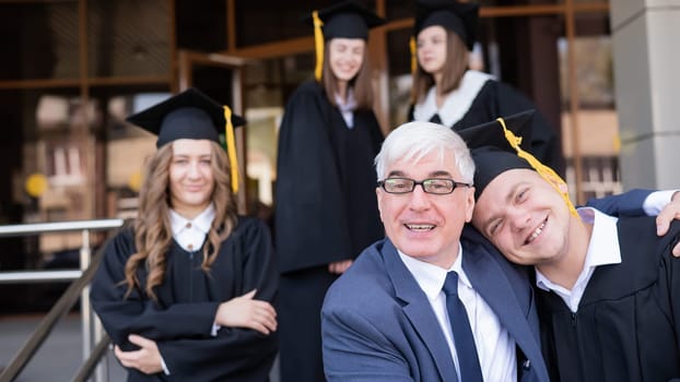 Father and son embrace at graduation. Parent congratulates university graduate