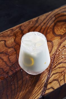 Slice of lemon inside. Close up view of fresh summer cocktail on the wooden table.