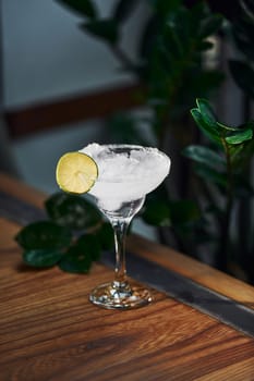 Piece of lime on top. Close up view of fresh summer cocktail on the wooden table.