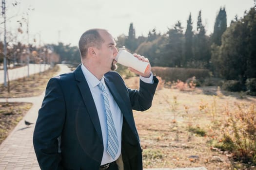 Mature entrepreneur drink coffee in autumn park. Senior executive rest in city park.