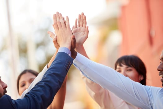 United in the same mission. a group of businesspeople high fiving together outdoors