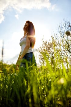 cute woman in summer clothes standing in a field of tall grass, bottom view. High quality photo