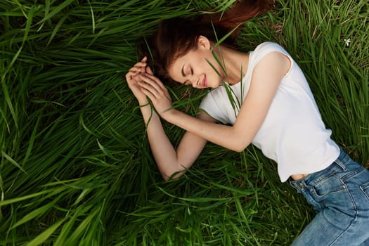 serene, woman lies in green tall grass in casual clothes. High quality photo