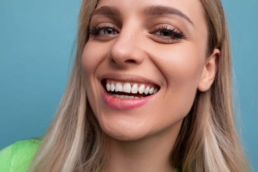 close-up of a healthy young blond woman with straight teeth on a blue background.