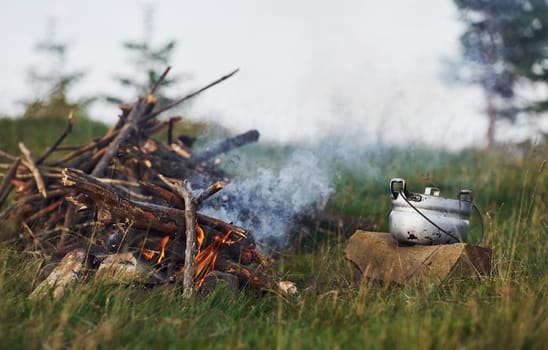 Active campfire on the meadow at daytime. Cloudy weather.