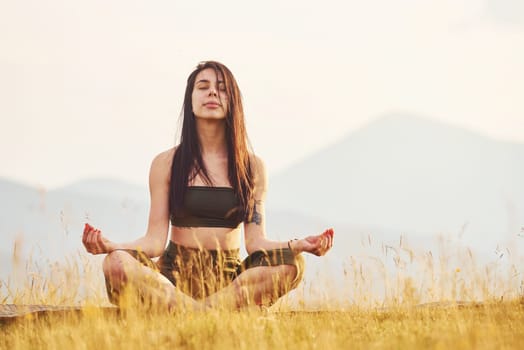 Beautiful young woman doing yoga exercises. Majestic Carpathian Mountains. Beautiful landscape of untouched nature.