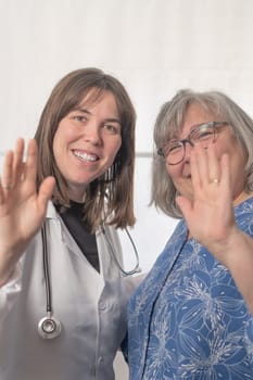 woman doctor and patient greeting the camera happy and smiling in the doctor's office