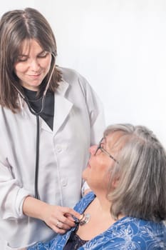 young doctor auscultating her patient's chest while they both smile