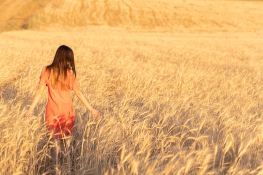 Unrecognizable woman in the wheat field. Moments of joy. Arms out to the side. Copy space.