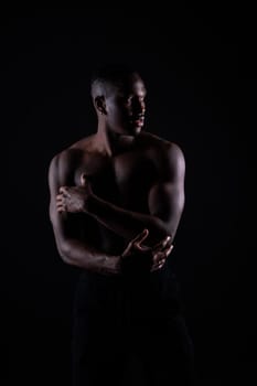 One young african muscular build man standing topless silhouette isolated on a black background