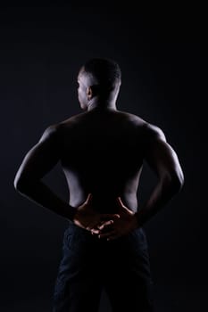 One young african muscular build man standing topless silhouette isolated on a black background