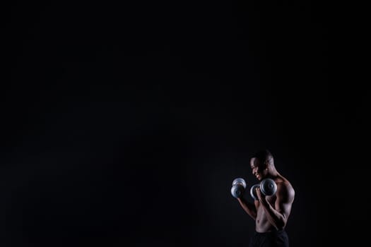 One young african muscular build man standing topless silhouette isolated on a black background