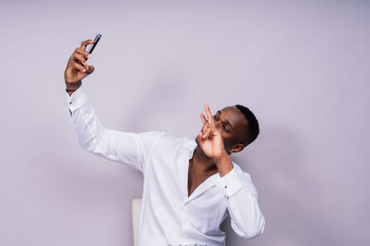 Handsome excited young african business man with a mobile phone isolated over gray background