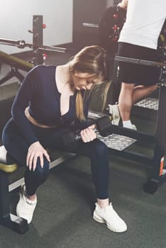 Woman doing biceps curl with dumbbells in seated position. white sneakers