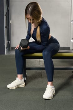 Woman doing biceps curl with dumbbells in seated position. white sneakers