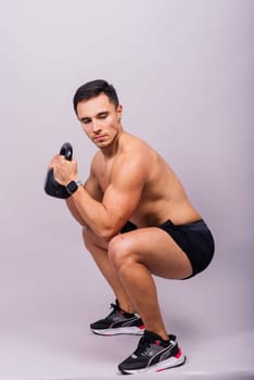 Strong young muscular focused fit man with a big muscles holding heavy kettlebells