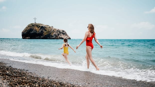 Happy loving family mother and daughter having fun together on the beach. Mum playing with her kid in holiday vacation next to the ocean - Family lifestyle and love concept.