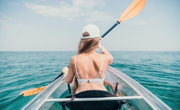 Woman in kayak back view. Happy young woman with long hair floating in transparent kayak on the crystal clear sea. Summer holiday vacation and cheerful female people having fun on the boat.