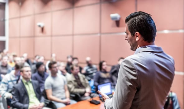 Speaker giving a talk on corporate business conference. Unrecognizable people in audience at conference hall. Business and Entrepreneurship event.