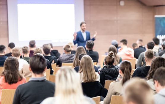 Speaker giving a talk in conference hall at business event. Audience at the conference hall. Business and Entrepreneurship concept. Focus on unrecognizable people in audience.