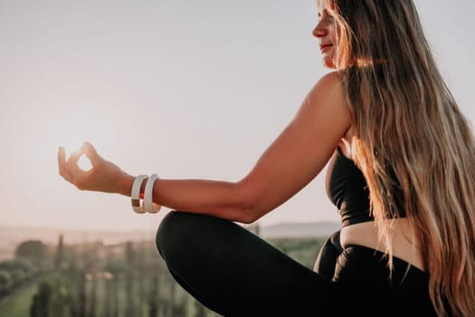 Well looking middle aged woman with long hair, fitness instructor in leggings and tops doing stretching and pilates on the rock near forest. Female fitness yoga routine concept. Healthy lifestyle.