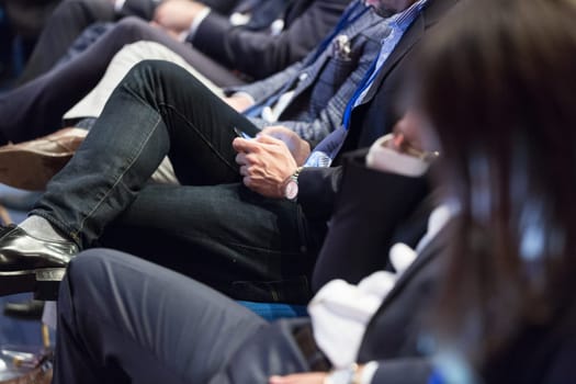 Row of unrecognizable business people sitting in conference hall at business event. Audience at business seminar. Business and Entrepreneurship concept.