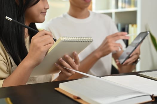 Tutor pointing at digital tablet, giving private educational lesson to focused teenage girl. Homeschooling and education concept.