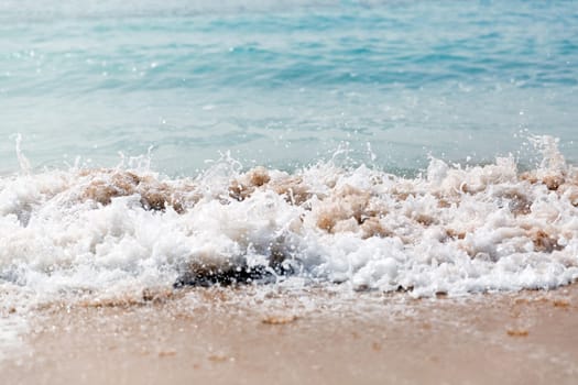 Close up sea waves with splashes on sand beach. Close up.