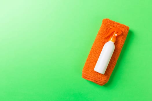 Summer beach flat lay accessories. Sunscreen bottle cream, towel and seashells on colored Background. Travel holiday concept with copy space.