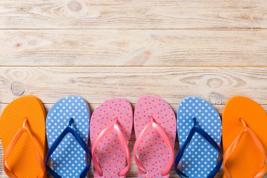 a lot of flip flop colored sandals, summer vacation on wooden background, copy space top view.