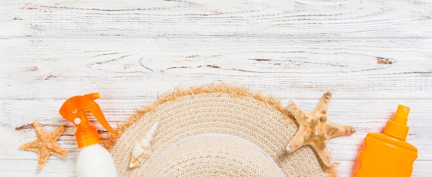 Sunscreen bottles with starfish and sunhat on white wooden table banner with copy space. Travel healthcare accessories top view.