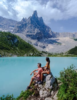 Couple of men and women visiting Lago di Sorapis in the Italian Dolomites, milky blue lake Lago di Sorapis, Lake Sorapis, Dolomites, Italy.