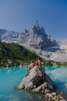 Couple of men and women visiting Lago di Sorapis in the Italian Dolomites, milky blue lake Lago di Sorapis, Lake Sorapis, Dolomites, Italy.