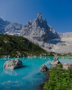 Couple of men and women visiting Lago di Sorapis in the Italian Dolomites, milky blue lake Lago di Sorapis, Lake Sorapis, Dolomites, Italy.