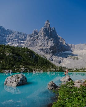 Couple of men and women visit Lago di Sorapis in the Italian Dolomites, milky blue lake Lago di Sorapis, Lake Sorapis, Dolomites, Italy.