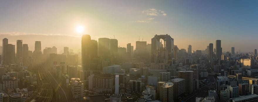 Bright sun rays through haze over downtown Osaka skyline in early morning. High quality photo