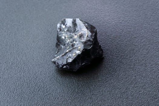 Black Obsidian stone on a black background. Natural glass. Black mineral gem