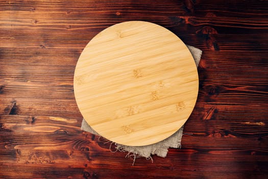 Round cutting board on a wooden kitchen table. Free space for your decoration