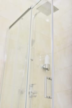 Shower, bathroom interior, light beige color, glass door with chrome handle close-up