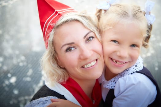 Young and adult schoolgirl on September with flowers having fun near water of fontain. Generations of schoolchildren, pioneer of USSR and October girl in modern uniform of Russia. Mom and daughter