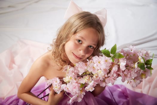 Portrait of cute kid girl posing in pink beautiful dress on white background. Model in studio looking as gentle magic princess from fairy taly having photo shoot on white background