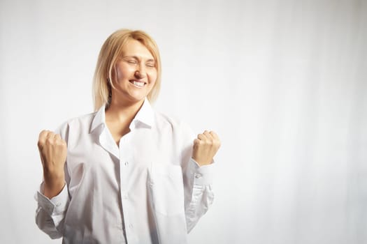 Portrait of a pretty blonde smiling woman posing on white background. Happy girl model in white shirt in studio. Lady winner is joyfull. Copy space