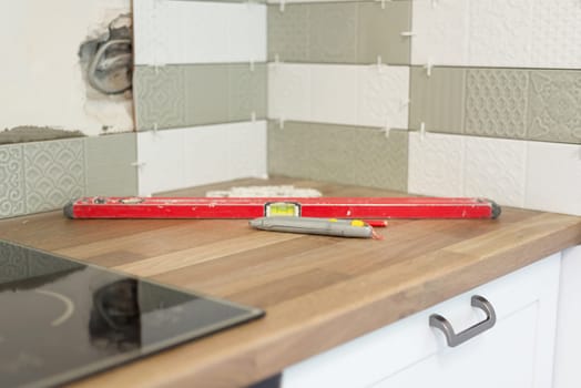 Close-up of tile laying, tiles glued to glue with cement, level fixture for smooth seams, nobody. Renovation, repair, construction