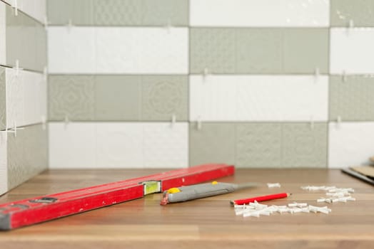 Close-up of tile laying, tiles glued to glue with cement, level fixture for smooth seams, nobody. Renovation, repair, construction