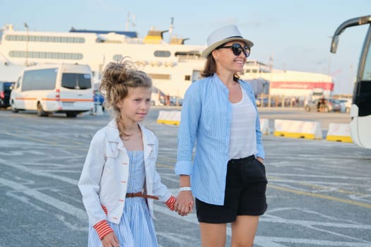 Mother and daughter child walking along seaport, family sea trip, summer vacation. Sea transport, ferry at port background