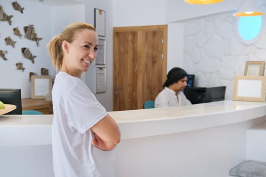 Portrait of spa hotel workers, man and woman near reception, bright interior of resort hotel background