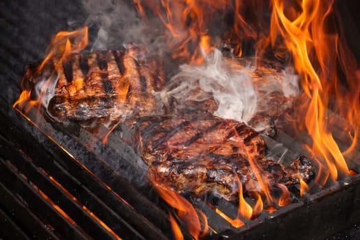 Close up searing and smoking ribeye beef steaks on open fire outdoor grill with cast iron metal grate, high angle view